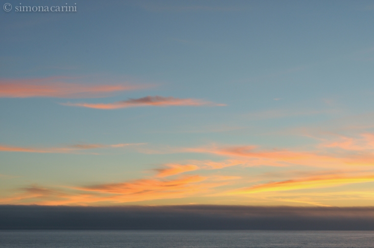 after sunset on the Pacific Ocean with stripes of clouds and fog at the horizon